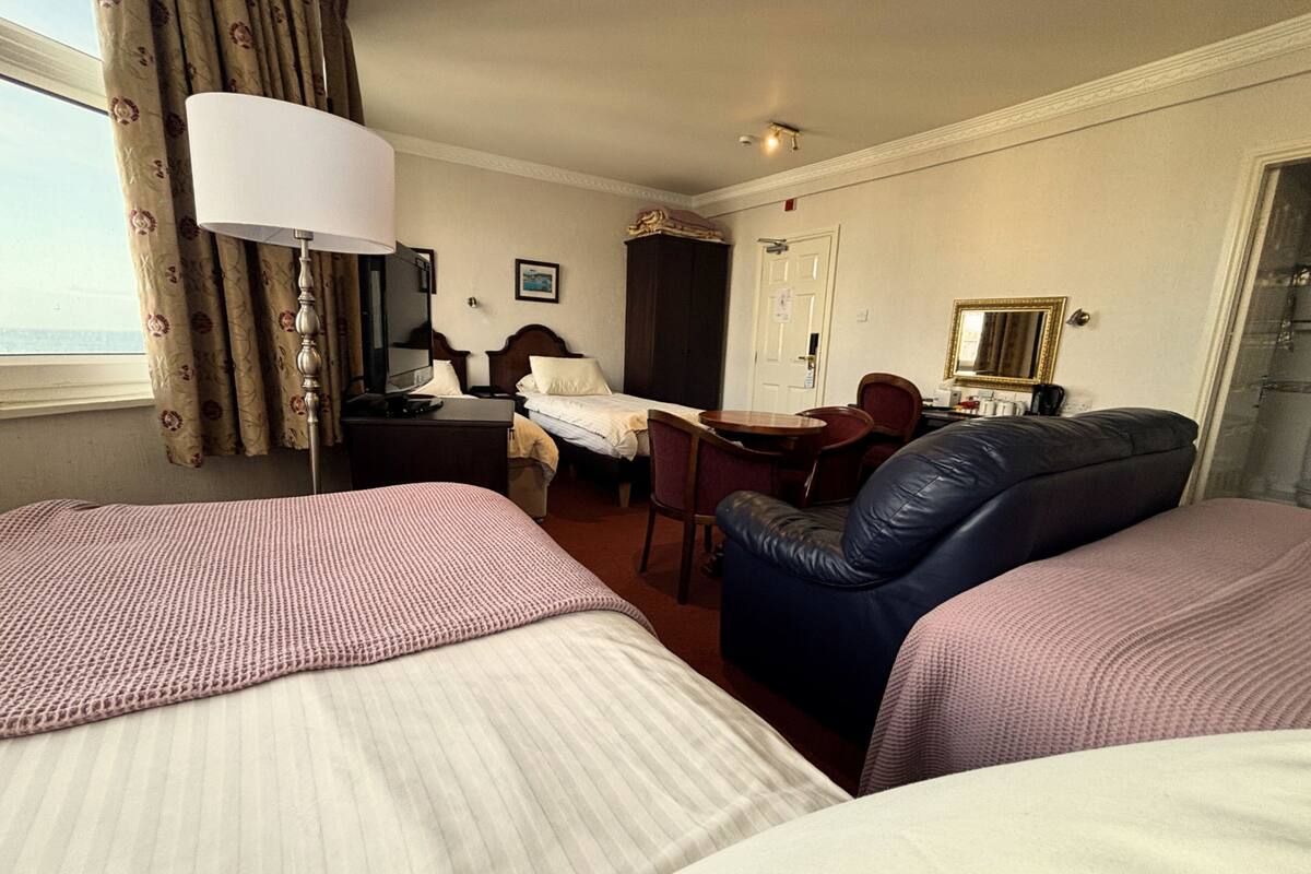 Une chambre d’hôtel avec deux lits, un bureau, une chaise, une lampe, un miroir et une porte.