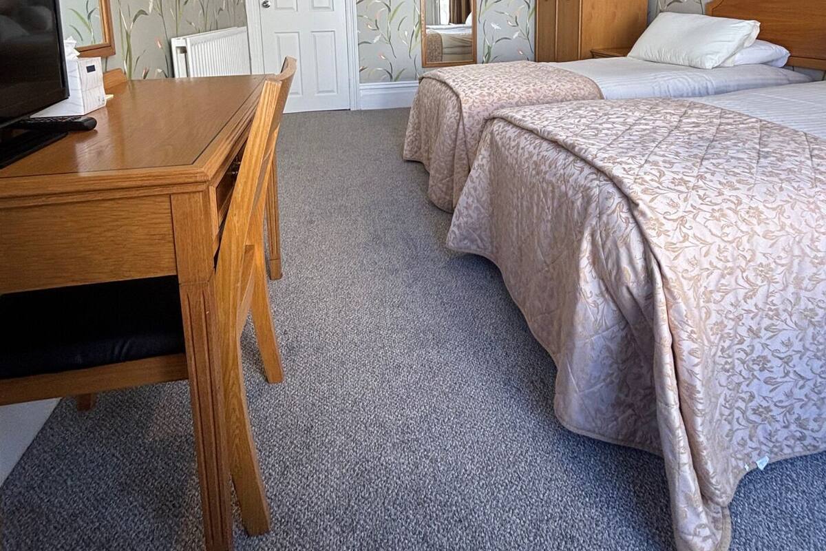 Une chambre d’hôtel avec deux lits, un bureau en bois, une télévision et une armoire.