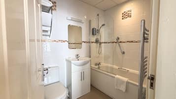 A compact bathroom with a toilet, sink, and glass-enclosed shower area.