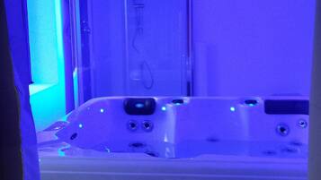 A hot tub with a glass enclosure, visible water jets, and a control panel.