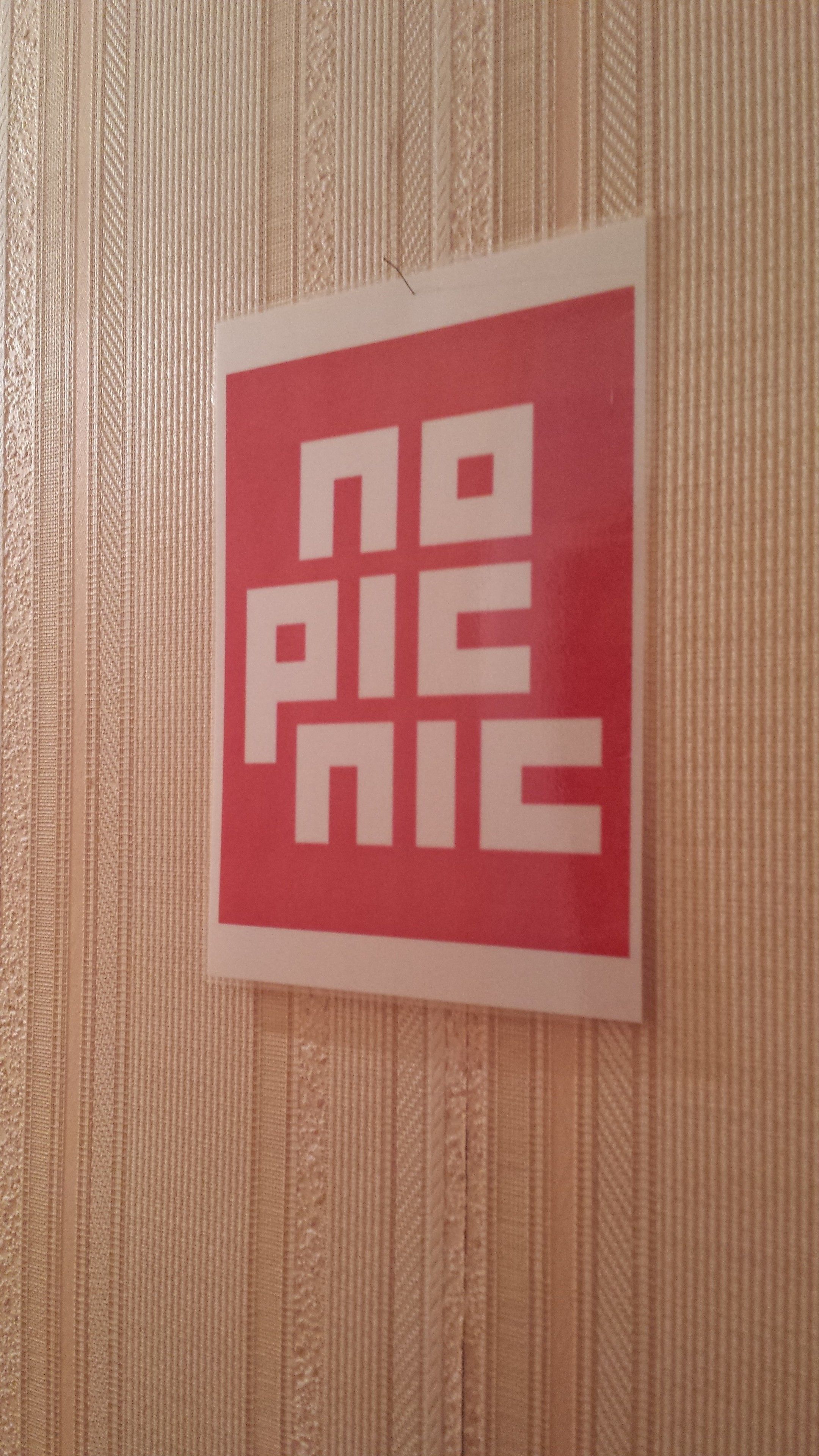 A red sign with white text on a textured wall.