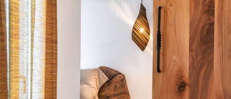 A wooden staircase leading to a bedroom with a bed, a hanging light fixture, and a wooden door.