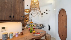 A kitchen with wooden cabinets, a round wooden table, and a fruit display. - Ayama Hideaway Villa by Calm Collection (Santorini)