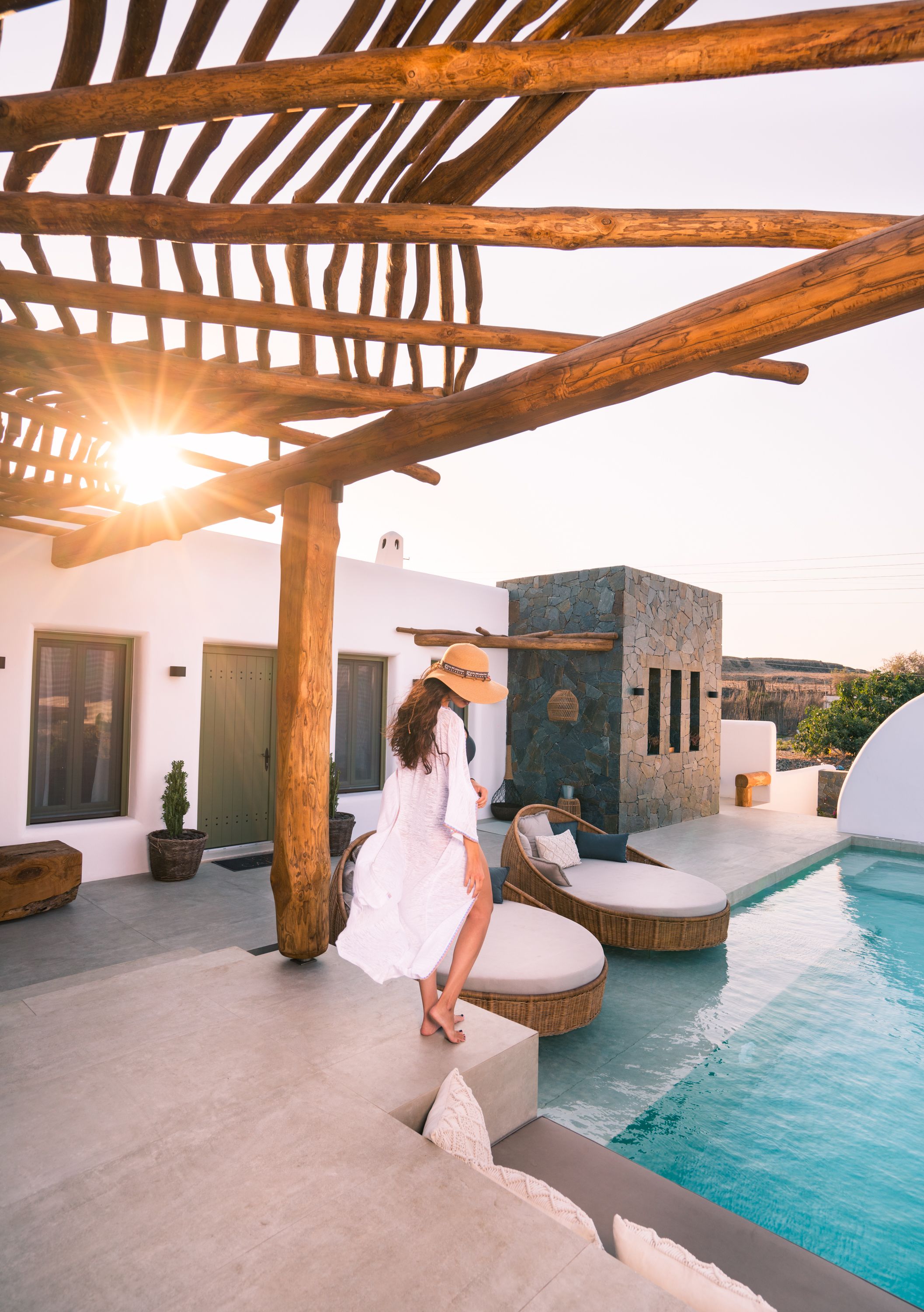 Un espace aménagé au bord de la piscine, avec une pergola, un mur en pierre et une vue sur le paysage.