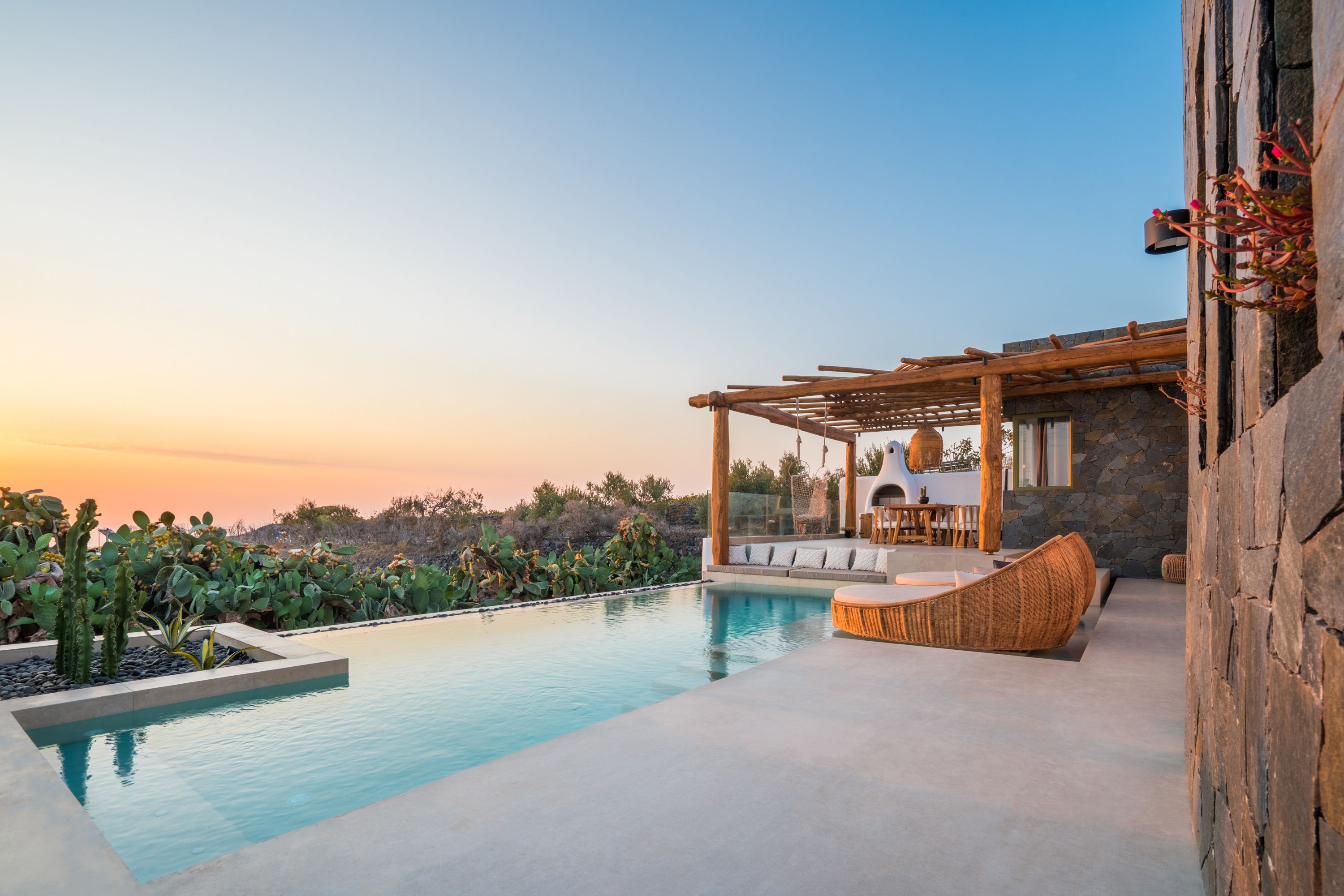 A pool area with a pergola, stone wall, and outdoor seating.