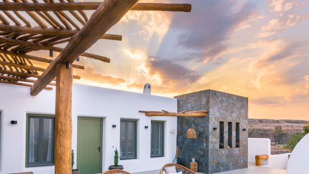 A modern outdoor pool area with wicker loungers and a stone wall. - Ayama Hideaway Villa by Calm Collection (Santorini)