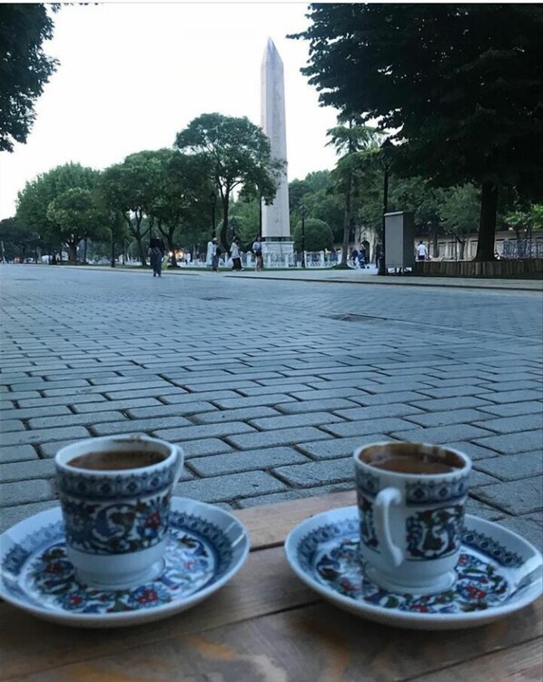 Two cups of coffee on saucers in a public square with a monument in the background.