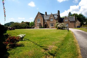 A large stone building with multiple windows and a well-maintained lawn in front.