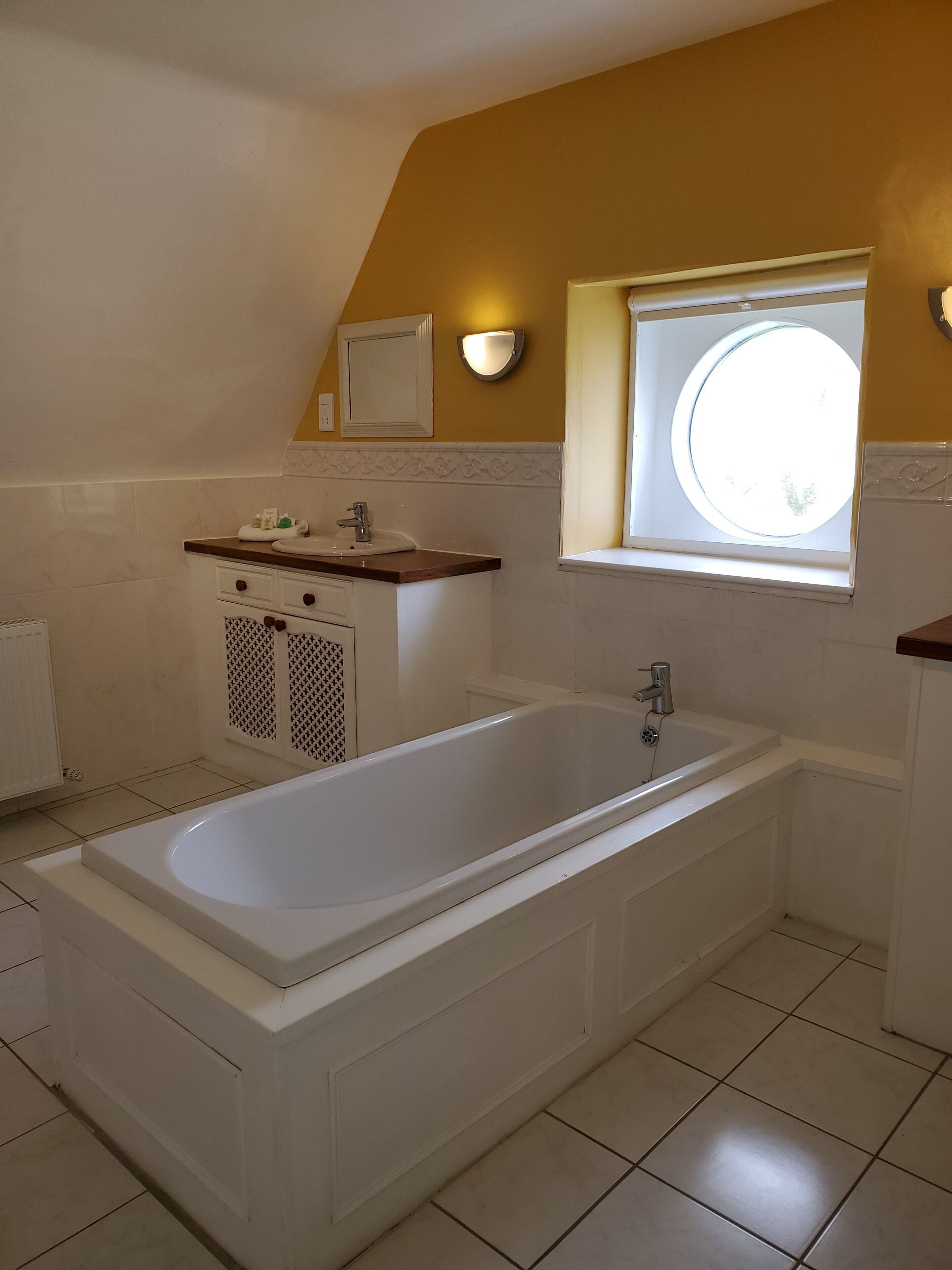 A modern bathroom with a freestanding bathtub, a vanity with a mirror, and a window providing natural light.