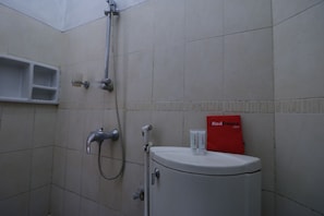 A bathroom with a toilet, a shower, and a shelf with toiletries. - RedDoorz Plus near Undip Tembalang (Semarang)