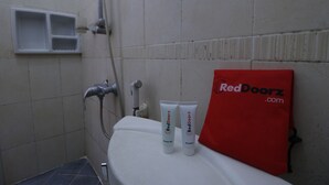 A bathroom with a shower, a toilet, and RedDoorz branded shower gel and shampoo. - RedDoorz Plus near Undip Tembalang (Semarang)