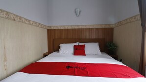 A neatly made bed with a red and white bedspread, a wooden headboard, and a single red pillow. - RedDoorz Plus near Undip Tembalang (Semarang)