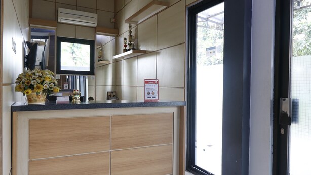 A modern kitchen with wooden cabinets, a built-in stove, and a large window. - RedDoorz Plus near Undip Tembalang (Semarang)