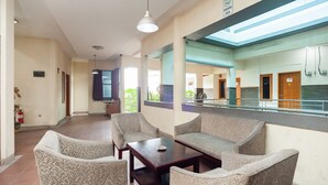 A spacious lobby with a seating area featuring sofas and armchairs, a fire extinguisher, and a sign indicating a smoking area.