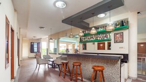 A bar area with a counter, stools, and hanging lights.