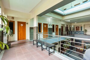 Un espacio interior de varios niveles con una escalera central, barandillas de vidrio y múltiples puertas.