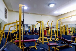 Un gimnasio con varios equipos de ejercicio, entre ellos bancos y máquinas de pesas.