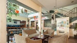 A spacious indoor area with seating arrangements, a staircase, and a RedDoorz vending machine.