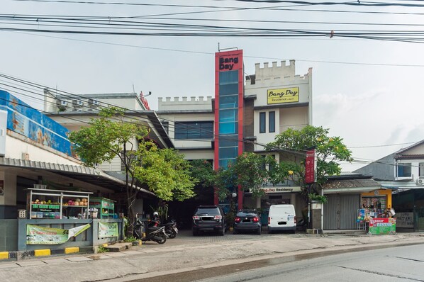 Un edificio con un letrero que dice 'Bang Day', un complejo residencial y una pequeña tienda con un cartel.