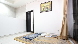 Une pièce avec un grand tapis, une porte, un tableau encadré au mur et un rideau.