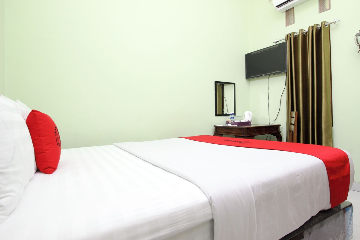Una habitación de hotel con una cama, un televisor en la pared y una cortina.