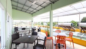 An outdoor dining area with tables and chairs, a covered section with a metal roof, and a view of the surrounding area. - RedDoorz Plus near Taman Sari (Yogyakarta)