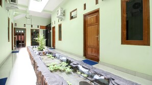 A hotel corridor with a long reception desk, wooden doors, and a blue carpet. - RedDoorz Plus near Taman Sari (Yogyakarta)
