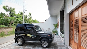 A black SUV parked on a patterned tile driveway next to a building with a wooden door. - RedDoorz Plus near Taman Sari (Yogyakarta)