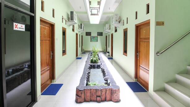 A hallway with a central planter, doors numbered 2 and 7, and a no-smoking sign on the left. - RedDoorz Plus near Taman Sari (Yogyakarta)