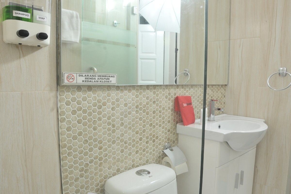 A bathroom with a toilet, sink, and hand soap dispenser.