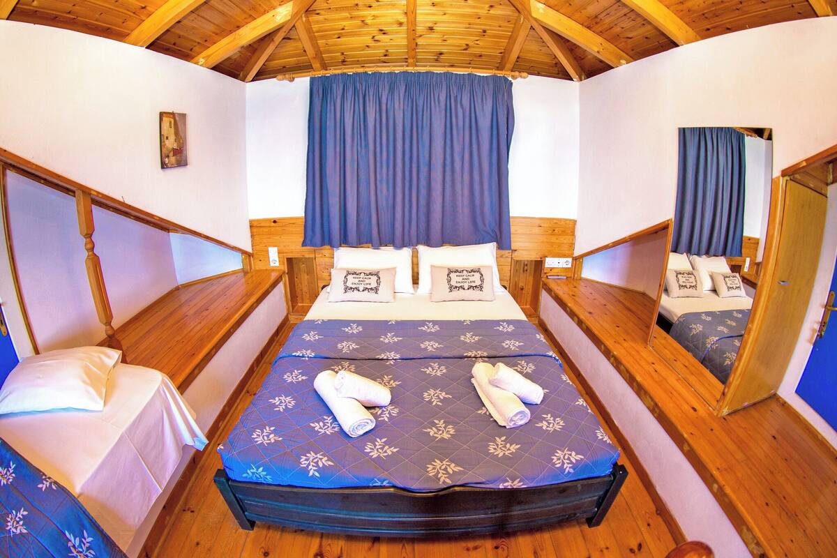 A room with two beds, wooden flooring, and a sloped ceiling.