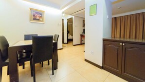 A dining area with a table and chairs, a kitchen with cabinets, and a hallway leading to another room. - RedDoorz Plus @ Project 6 Quezon City (Quezon City)