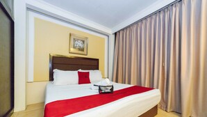 A hotel room with a large bed, a headboard, a framed picture on the wall, and a window with curtains. - RedDoorz Plus @ Project 6 Quezon City (Quezon City)