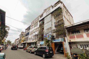 Une vue de rue d’un immeuble à étages, doté de balcons et de divers panneaux, dont un indiquant un cabinet d’avocats.