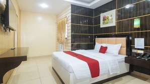 A hotel room with a bed, a desk, a telephone, and a wall-mounted picture. - RedDoorz @ Winter Hotel Araneta (Quezon City)