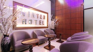 A reception area with a 'WINTER HOTEL' sign, sofas, and a coffee table. - RedDoorz @ Winter Hotel Araneta (Quezon City)