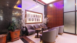 A lobby with a reception desk, sofas, and a large sign reading "Winter Hotel". - RedDoorz @ Winter Hotel Araneta (Quezon City)
