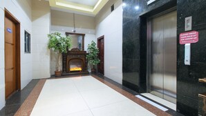 A lobby with a fireplace, potted plants, and an elevator. - RedDoorz @ Winter Hotel Araneta (Quezon City)
