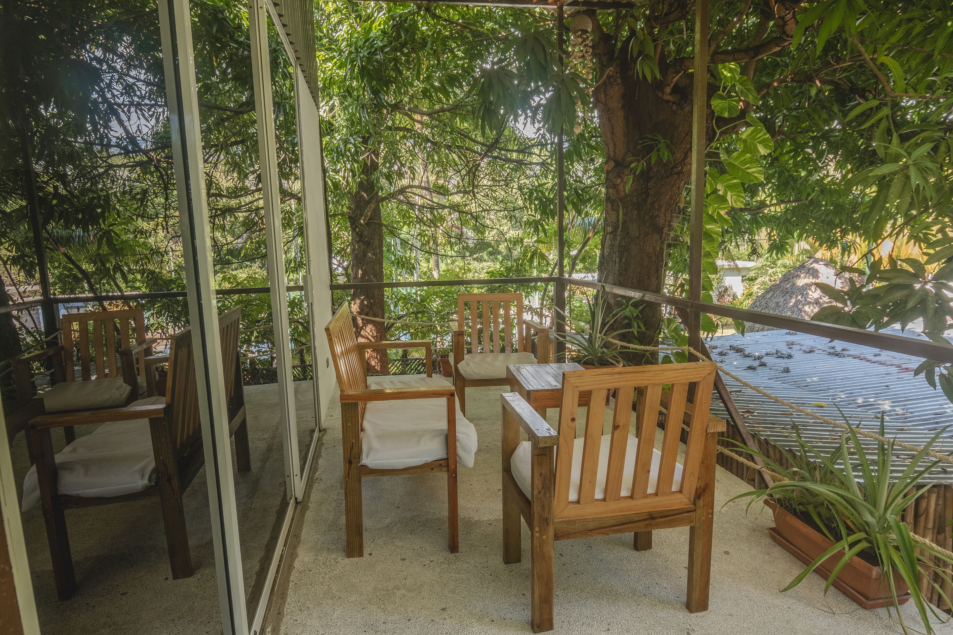 Un espacio de estar al aire libre techado, con mobiliario de madera y vistas a vegetación exuberante.