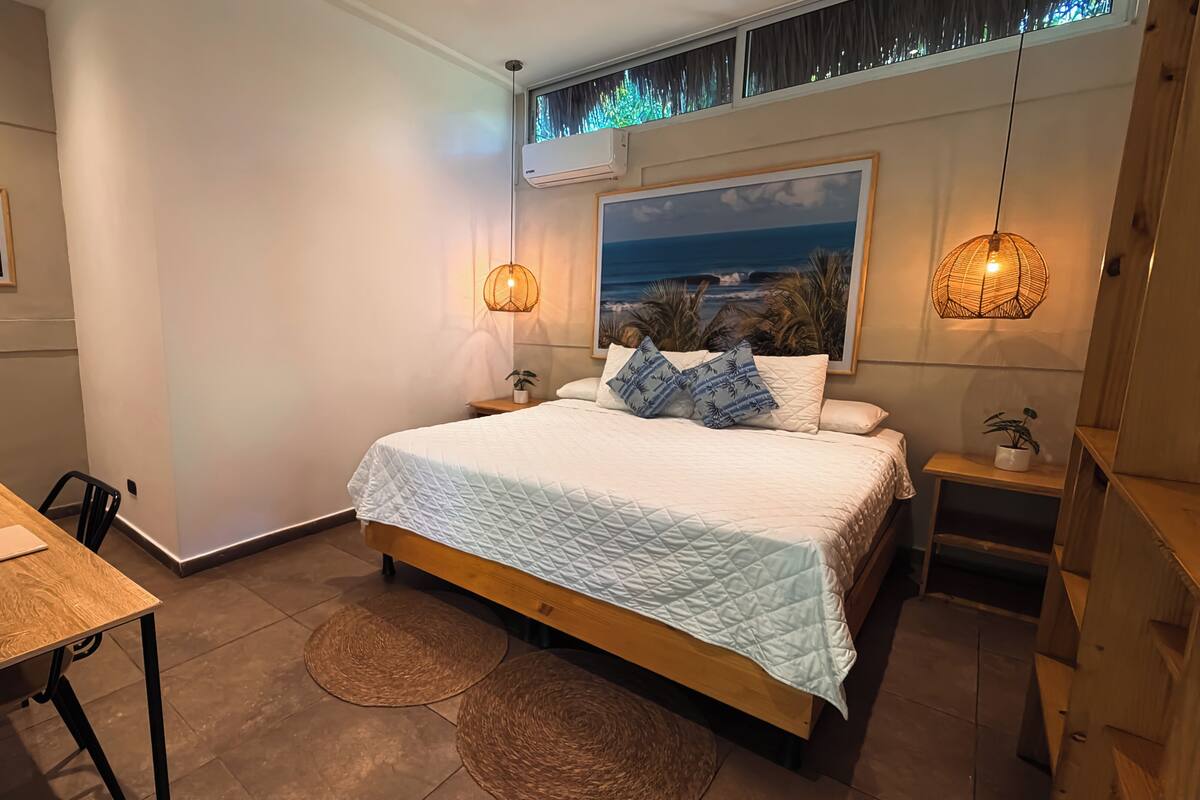 A bedroom with a bed, bedside tables, a desk, and a chair.