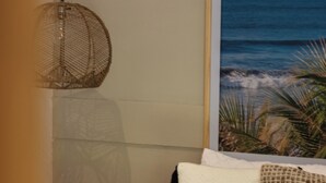 A bedroom with a bed, a hanging light fixture, a framed picture of the ocean, and a small potted plant. - Hotel Michanti (Chiltiupan)