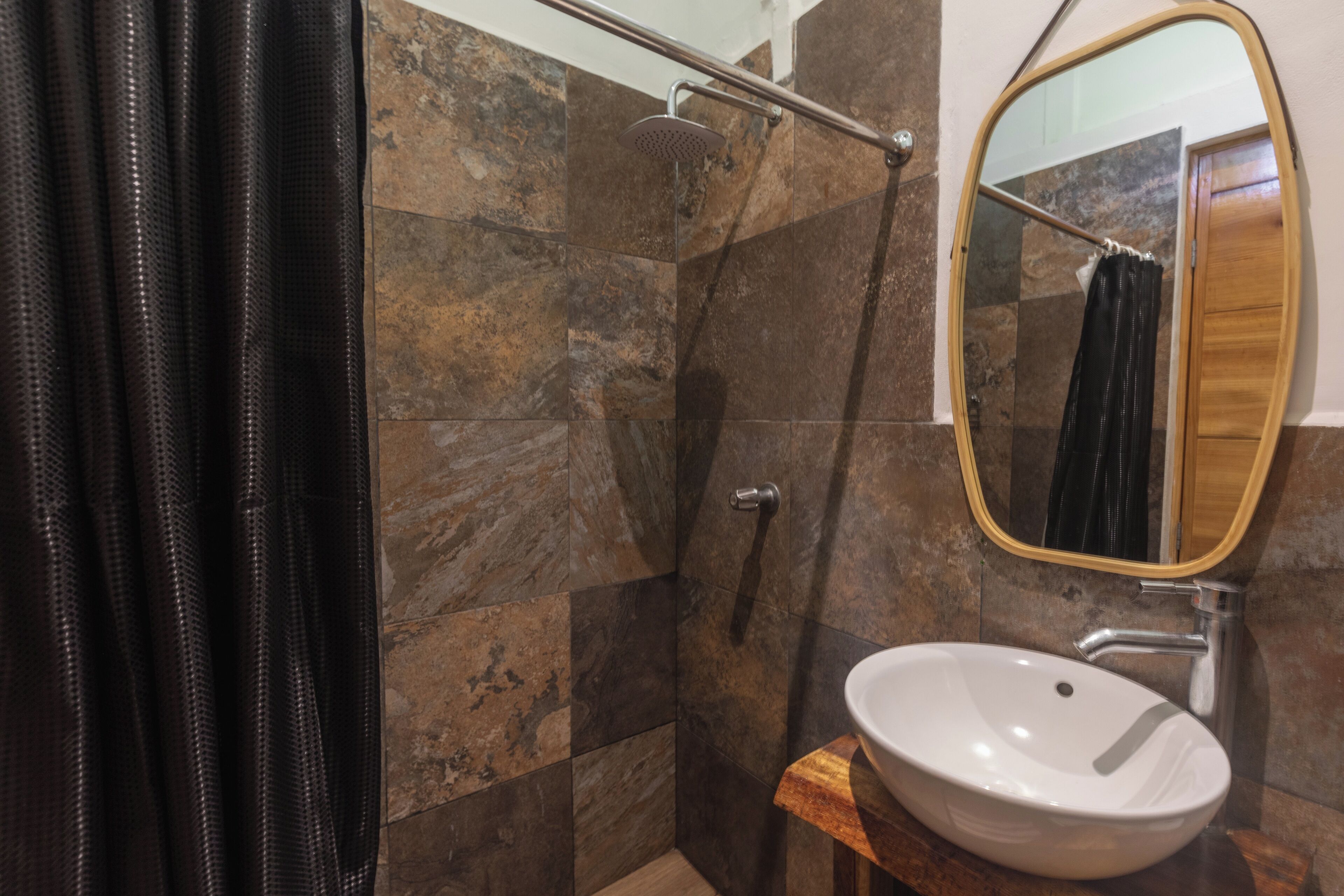 A bathroom with a shower, a sink, and a mirror.