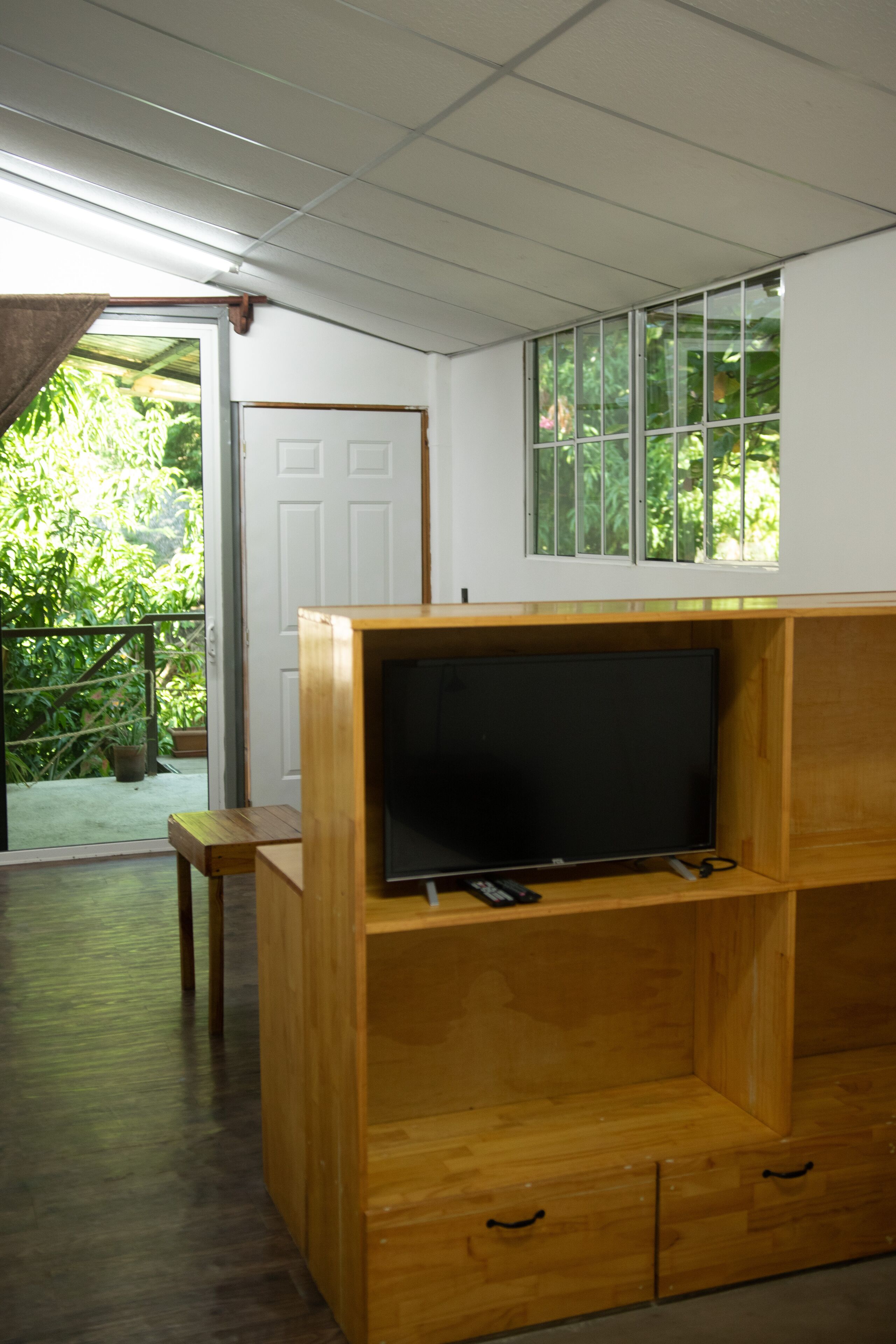 A wooden entertainment unit with a flat-screen TV, drawers, and a window above it.