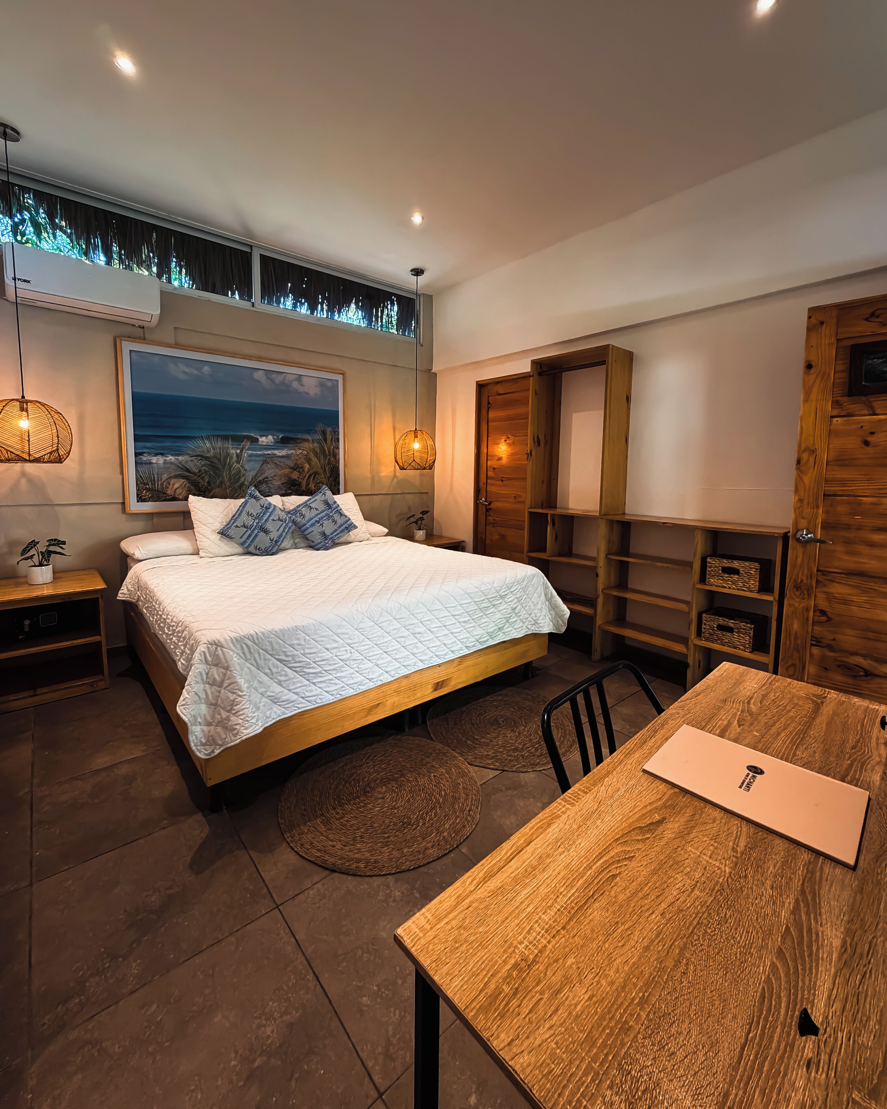 Un dormitorio moderno con una cama grande, muebles de madera, vista al océano y un comedor.