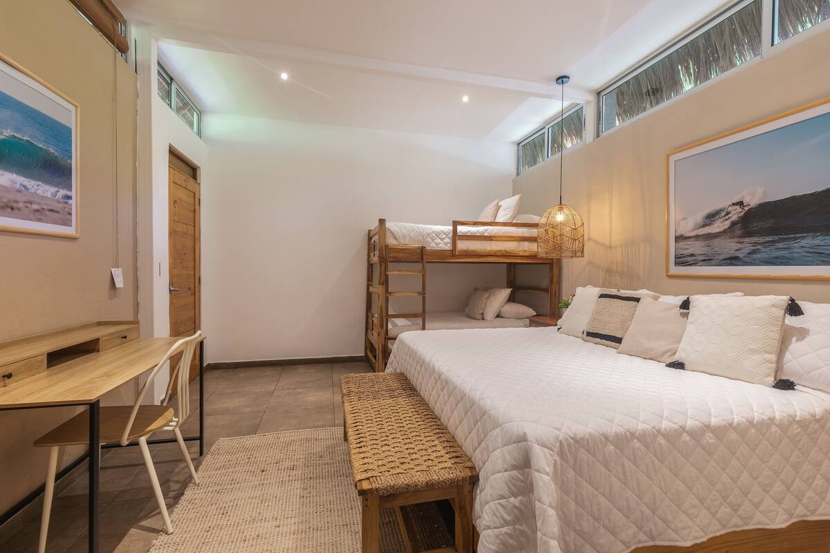 A bedroom with a bunk bed, a desk, and a bench.
