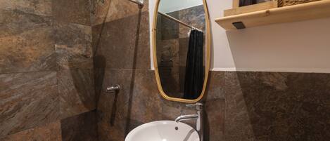 A bathroom with a white sink, a mirror, and a shower area.
