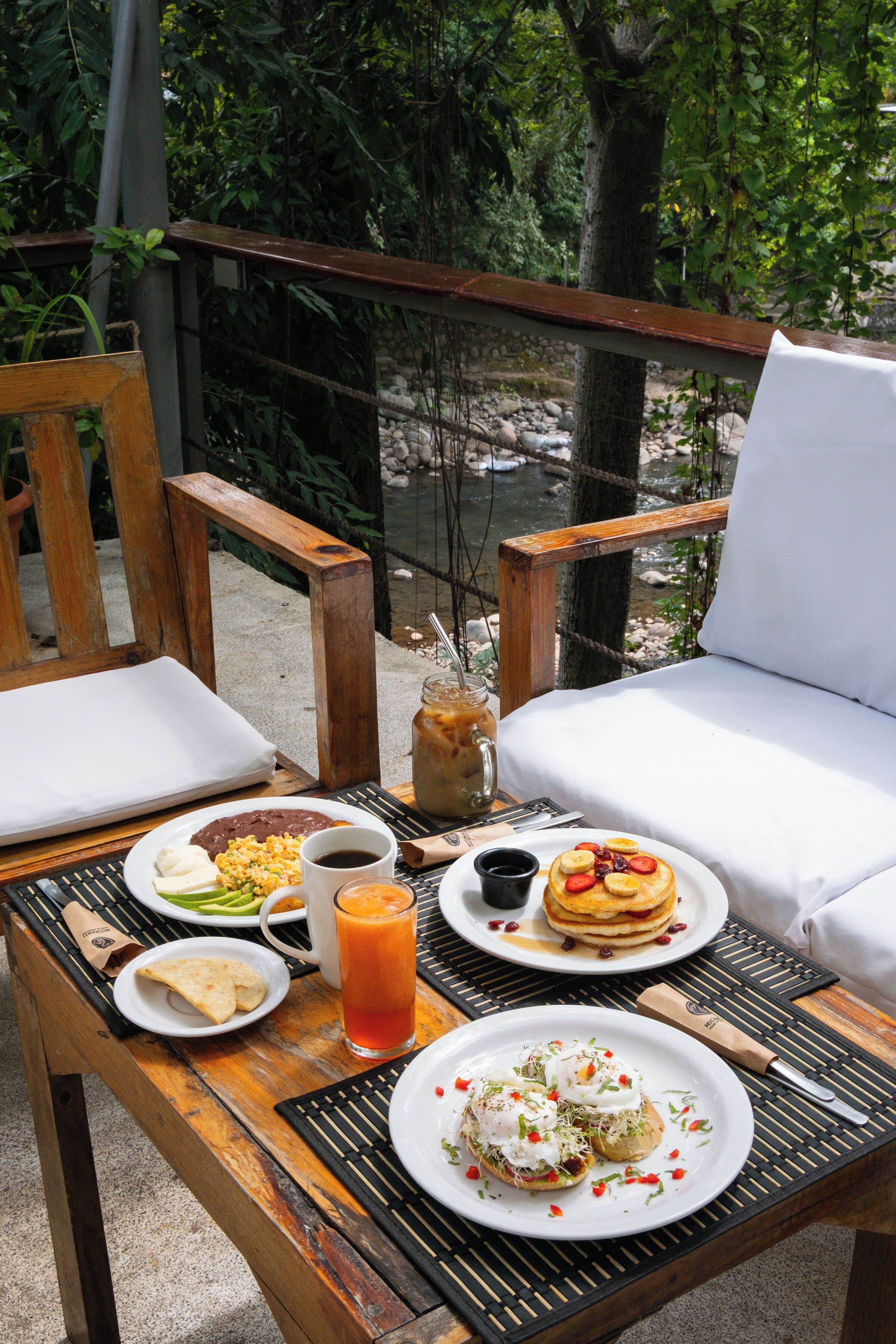 A dining table with various breakfast items, a chair, and a view of a natural landscape.