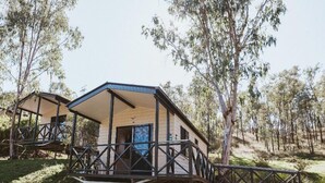 Una cabaña de dos pisos con balcón, rodeada de árboles.