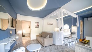 Una sala de estar moderna con un sofá, una mesa redonda y una cama con dosel blanco.