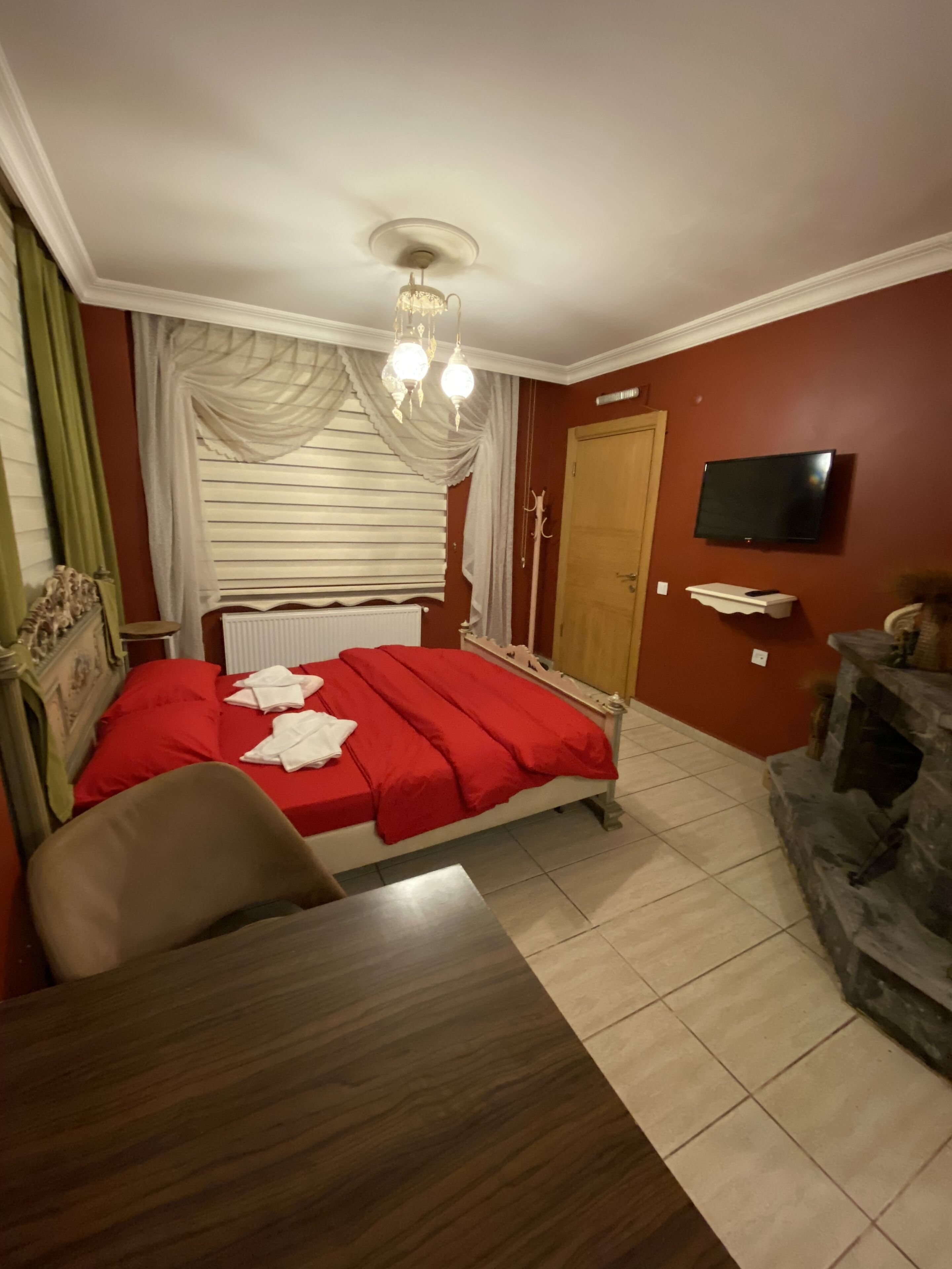 A bedroom with a bed, a TV, a fireplace, and a dining table.